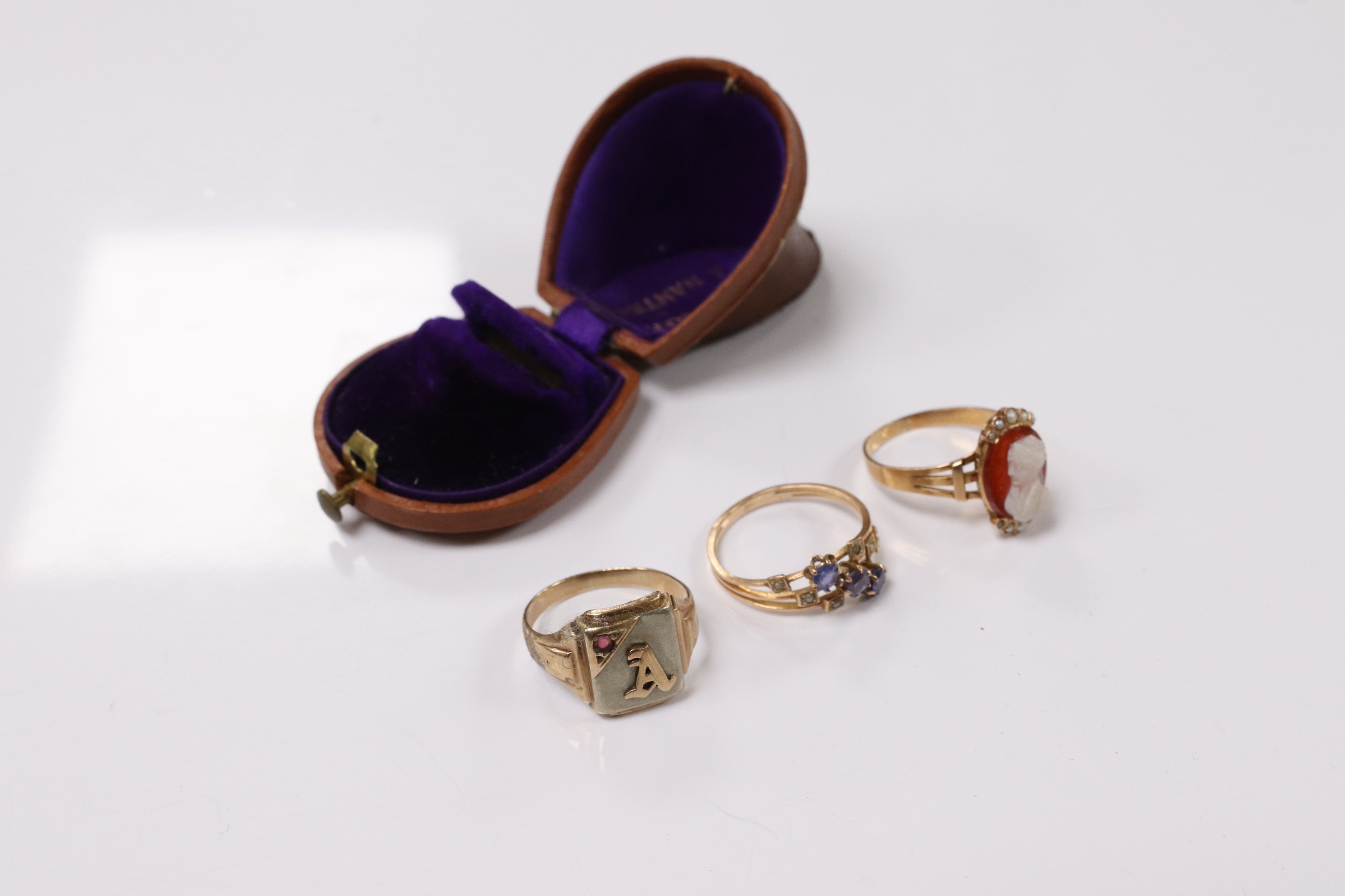 A 10k and gem set initial ring, a continental yellow metal and gem set ring and an early 20th century yellow metal, hardstone cameo and seed pearl set ring, size P, gross weight 8.2 grams. Condition - poor to fair